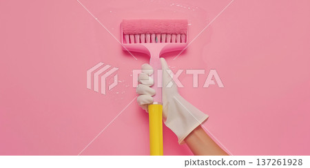 Hand holding a cleaning roller against a pink wall in a home cleaning setting Hand holding a cleaning roller against a pink wall in a home cleaning setting 137261928