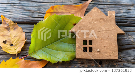Wooden house model placed among autumn leaves on a rustic wooden surface Wooden house model placed among autumn leaves on a rustic wooden surface 137261933