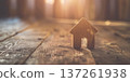 Wooden house figurine on rustic surface with warm sunlight creating a cozy home atmosphere 137261938