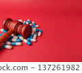 This image depicts a judge's gavel resting on a pile of pill capsules. 137261982