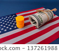 Model oil barrel and rolled-up US currency on an American flag. 137261988