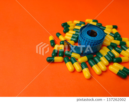 Collection of capsules and a measuring tape on a orange background. Collection of capsules and a measuring tape on a orange background. 137262002