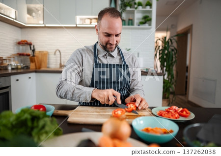 Man in apron slicing fresh tomatoes for healthy meal 137262038