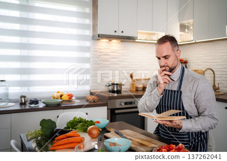 Man reading cookbook in kitchen preparing healthy meal 137262041