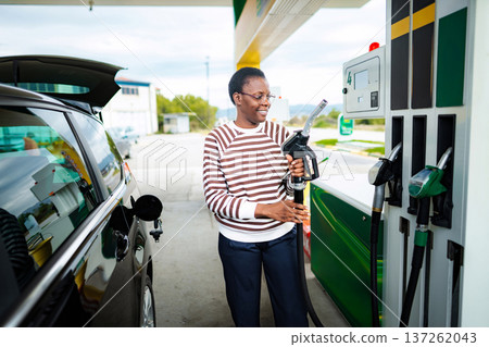 Mid adult woman refueling car at gas station Mid adult woman refueling car at gas station 137262043