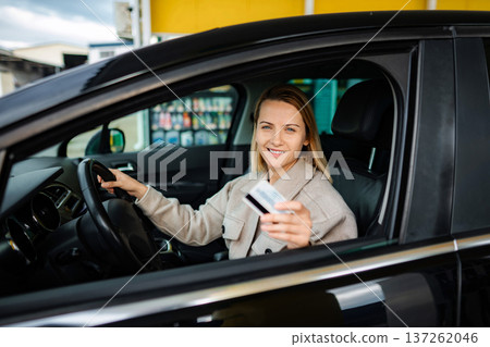 Woman in car holding credit card at gas station Woman in car holding credit card at gas station 137262046