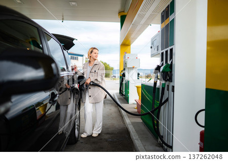 Woman fueling black car at a gas station Woman fueling black car at a gas station 137262048