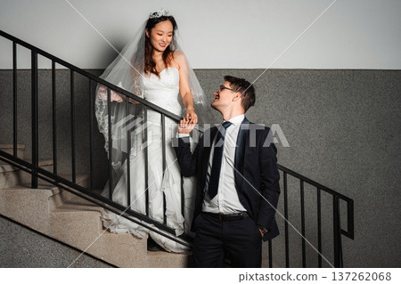 Interracial wedding couple holding hands walking down stairs Interracial wedding couple holding hands walking down stairs 137262068