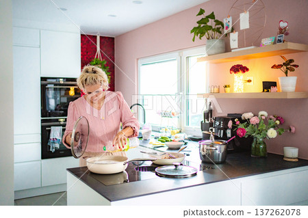 Woman preparing healthy meal in modern pink kitchen Woman preparing healthy meal in modern pink kitchen 137262078