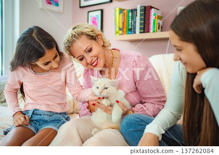 Family bonding with pet cat at home, three interacting Family bonding with pet cat at home, three interacting 137262084