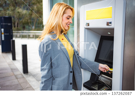 Woman inserting credit card into ATM for cash withdrawal 137262087