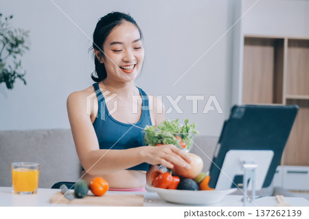 Fit young Asian women in activewear sitting on yoga mat and eating fresh vegetable salad after workout, representing clean eating, fitness lifestyle, wellness routine and health balance. Fit young Asian women in activewear sitting on yoga mat and eating fresh vegetable salad after workout, representing clean eating, fitness lifestyle, wellness routine and health balance. 137262139