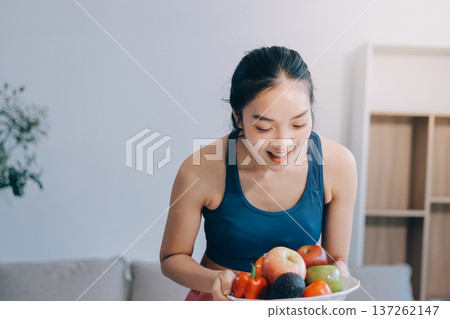 Fit young Asian women in activewear sitting on yoga mat and eating fresh vegetable salad after workout, representing clean eating, fitness lifestyle, wellness routine and health balance. Fit young Asian women in activewear sitting on yoga mat and eating fresh vegetable salad after workout, representing clean eating, fitness lifestyle, wellness routine and health balance. 137262147
