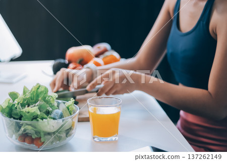 Fit young Asian women in activewear sitting on yoga mat and eating fresh vegetable salad after workout, representing clean eating, fitness lifestyle, wellness routine and health balance. Fit young Asian women in activewear sitting on yoga mat and eating fresh vegetable salad after workout, representing clean eating, fitness lifestyle, wellness routine and health balance. 137262149