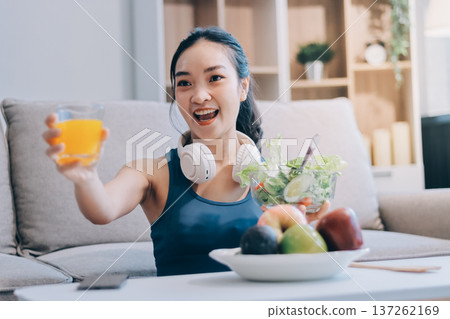 Fit young Asian women in activewear sitting on yoga mat and eating fresh vegetable salad after workout, representing clean eating, fitness lifestyle, wellness routine and health balance. Fit young Asian women in activewear sitting on yoga mat and eating fresh vegetable salad after workout, representing clean eating, fitness lifestyle, wellness routine and health balance. 137262169