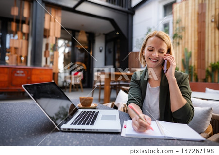 Woman working remotely at cafe making phone call 137262198