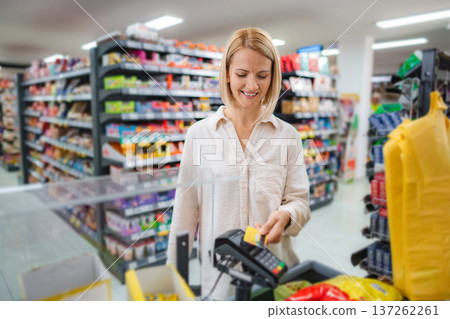 Woman paying for groceries using contactless credit card terminal 137262261