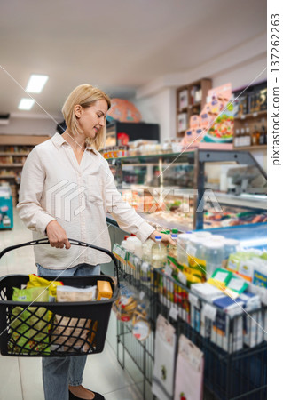 Woman shopping for groceries in supermarket with basket 137262263
