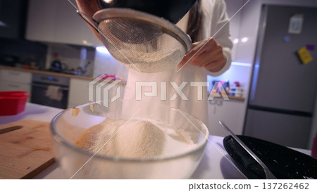 Consistent motion of hands pouring and sifting flour to prepare batter 137262462