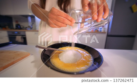 Closeup of hands mixing water into eggs in bowl demonstrating cooking tip Closeup of hands mixing water into eggs in bowl demonstrating cooking tip 137262471