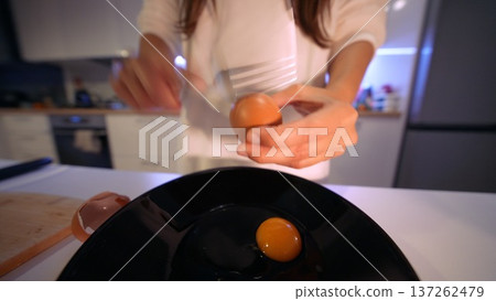 Detailed shot of hands cracking eggs into bowl during breakfast 137262479