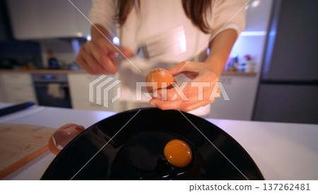 Closeup of hands carefully cracking egg into bowl with studio lighting Closeup of hands carefully cracking egg into bowl with studio lighting 137262481