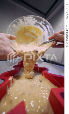 Home baker woman scraping batter into heart mold with spatula 137262485