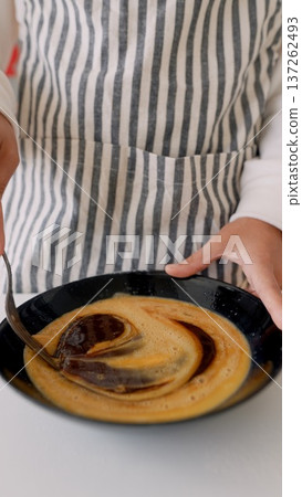 Closeup of hands blending caramel in cozy rustic kitchen setting 137262493