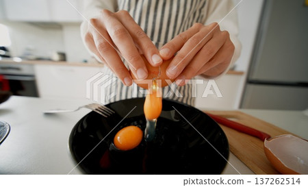 Precise technique shown in bright kitchen during egg cracking 137262514