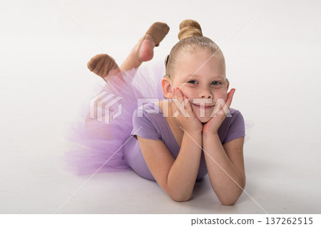 Little ballerina with cochlear implant lying on floor and smiling. Childhood inclusion, relaxation, and hearing awareness through art, grace, and joy. 137262515