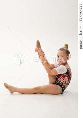Child rhythmic gymnast with cochlear implant performing leg extension exercise. Hearing loss treatment, cochlear implant rehabilitation, inclusive physical education, balance training, and motor 137262531