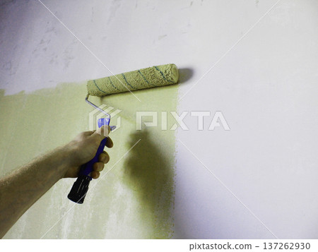 The master paints the wall in a different color. Roller painting technique. 137262930