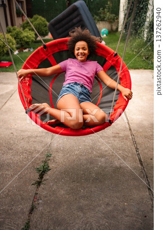 Happy black girl swinging on a backyard swing Happy black girl swinging on a backyard swing 137262940