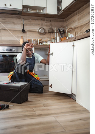 Handyman checking inside kitchen cabinet during house maintenance 137262957