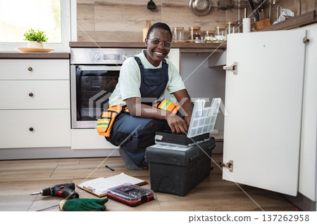 Female plumber searching tools in toolbox in kitchen sink cabinet Female plumber searching tools in toolbox in kitchen sink cabinet 137262958