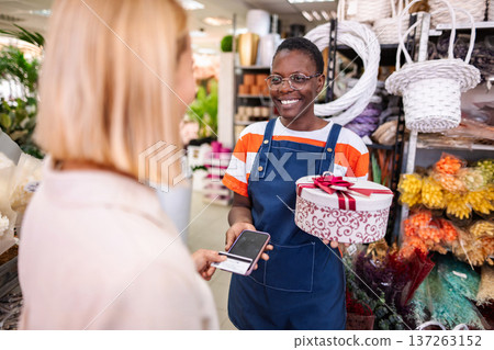 Florist receiving payment for gift box with smartphone in flower shop 137263152