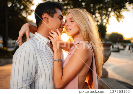 Lovers basking in the golden glow of sunset at a lively urban park Lovers basking in the golden glow of sunset at a lively urban park 137263163