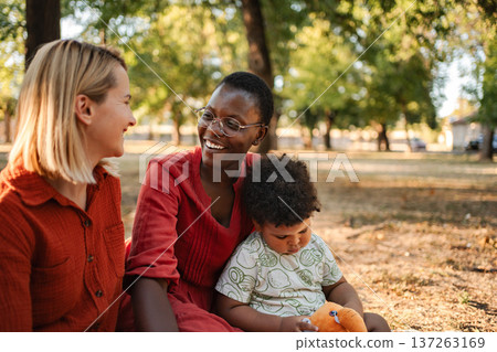 Two mothers and child enjoying a sunny day at the park 137263169