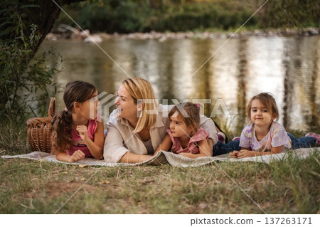 Mother and daughters enjoying a picnic by the river 137263171