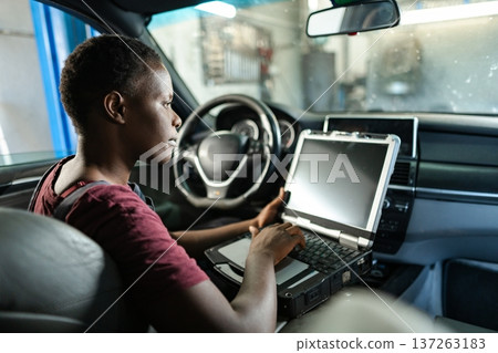 Car mechanic using a computer doing diagnostics on a vehicle 137263183