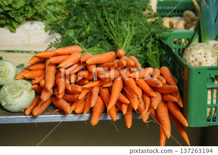 Pile of freshly harvested carrots at outdoor market stand. Healthy eating, organic farming, seasonal produce and sustainable agriculture concept Pile of freshly harvested carrots at outdoor market stand. Healthy eating, organic farming, seasonal produce and sustainable agriculture concept 137263194