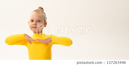 Young girl with cochlear implant performing dance pose in studio. Copy space. Hearing impairment rehabilitation, auditory therapy, assistive hearing technology, inclusive childhood development, and 137263496