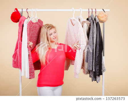 Woman standing in wardrobe picking winter outfit Woman standing in wardrobe picking winter outfit 137263573