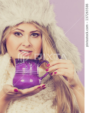 Woman wearing furry hat holding mug 137263586