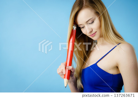 Woman confused thinking, big pencil in hand Woman confused thinking, big pencil in hand 137263671