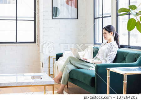 Young woman operating a personal computer in the living room 137264202