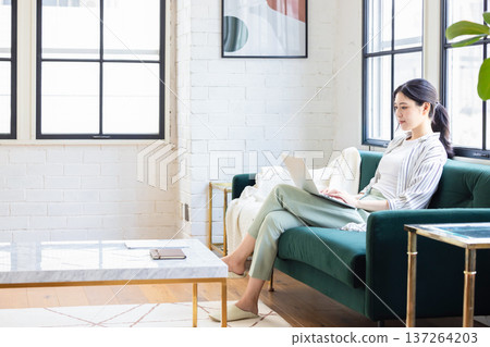 操作一台個人計算機的少婦在客廳 137264203
