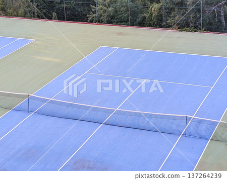 Blue and green tennis court with white lines and net. Sports tourism in mountain village. Blue and green tennis court with white lines and net. Sports tourism in mountain village. 137264239