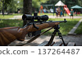 A rifle lying on a park bench, against a blurred backdrop of a playground and children. Conceptualizing gun control, public safety, and social risks. 137264487