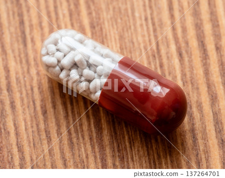 single medical capsule with granule on wood table single medical capsule with granule on wood table 137264701